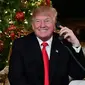 Presiden AS Donald Trump tersenyum saat berbicara di telepon pada malam natal di Palm Beach, AS (24/12). Donald Trump dan istrinya sibuk berbicara di telepon dengan anak-anak saat mengiktui NORAD Tracks Santa. (AFP Photo/Nicholas Kamm)