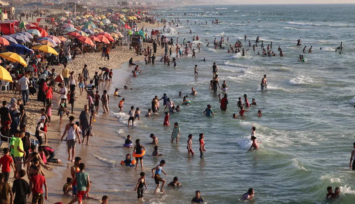 <p>Warga Palestina berkumpul di pantai Beit Lahia di Jalur Gaza utara saat para siswa memulai liburan musim panas mereka pada 3 Juni 2022. Sejumlah warga menikmati musim panas dengan berenang dan bermain air di pantai. (MOHAMMED ABED / AFP)</p>