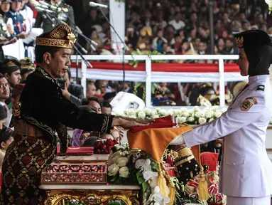 Presiden Joko Widodo menyerahkan duplikat bendera pusaka kepada Paskibraka Salma El Mutafaqqiha dalam Upacara Peringatan Detik-Detik Proklamasi Kemerdekaan Indonesia ke-74 Tahun 2019 di Istana Merdeka, Jakarta, Sabtu (17/8/2019).  (Liputan6.com/HO/Kentung)