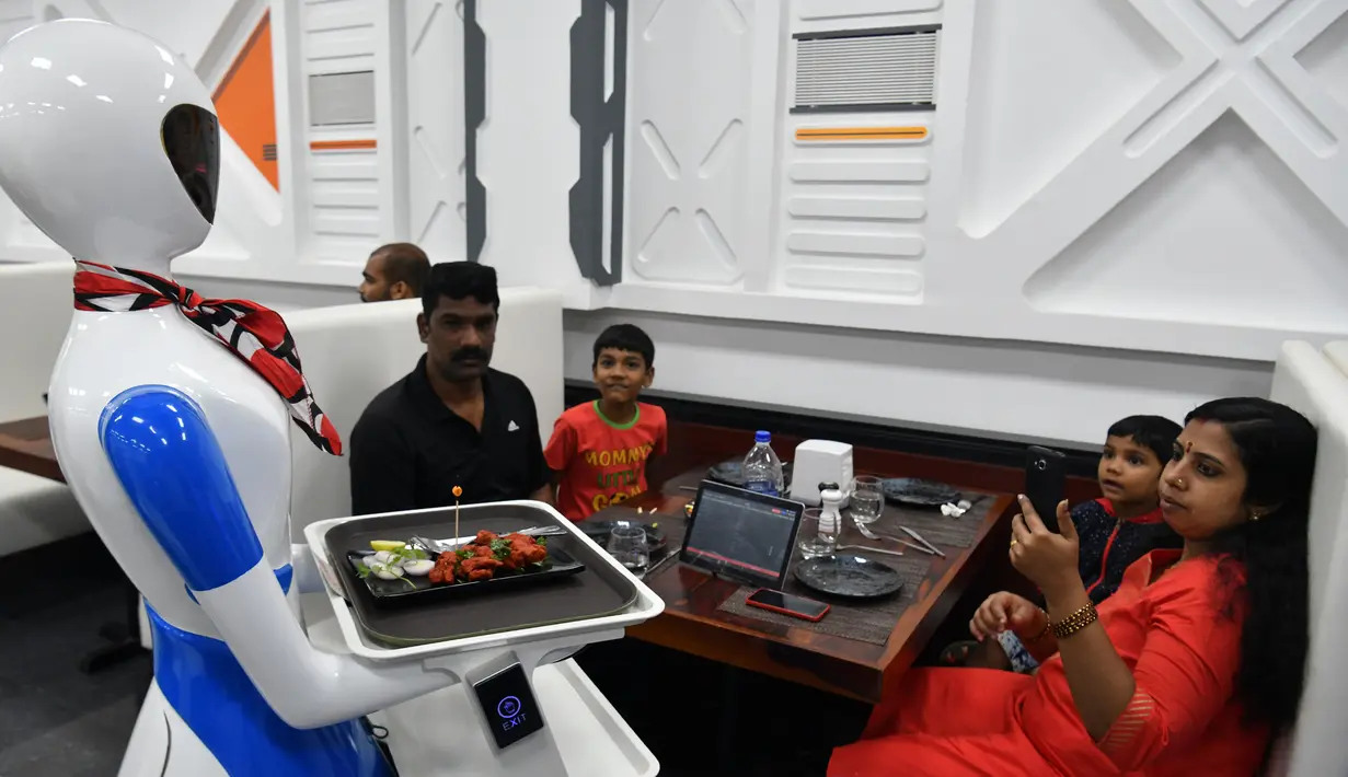 Sebuah robot mengantarkan pesanan makanan kepada pelanggan saat pembukaan restoran di Bangalore, India, Sabtu (17/8/2019). Restoran tersebut memperkenalkan satu robot pengantar serta lima robot untuk berinteraksi dan menyajikan makanan bagi para pelanggannya. (Manjunath Kiran/AFP)