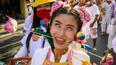 Seorang wanita menusuk pipinya dengan besi  saat mengikuti prosesi perayaan Festival Vegetarian tahunan di Phuket, Thailand, Kamis (3/10/2019). Festival ini biasanya berlangsung selama 9 hari di akhir September sampai Oktober. (AFP Photo/Mladen Antonov)