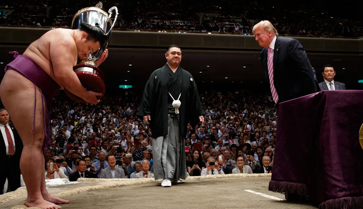 Presiden AS Donald Trump (kanan) memberi hormat kepada pemenang Tokyo Grand Sumo Tournament di Stadion Ryogoku Kokugikan, Tokyo, Jepang, Minggu (26/5/2019). Trump merupakan Presiden AS pertama yang menonton sumo di Jepang. (AP Photo/Evan Vucci)