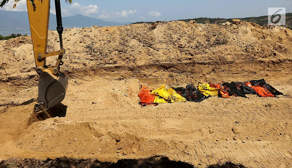 Puluhan jenazah dikubur massal menggunakan eskavator di TPU Peboya Indah, Palu, Sulawesi Tengah, Rabu (3/10). Jenazah yang merupakan korban gempa tsunami dikubur tiga lapis. (Liputan6.com/Fery Pradolo)