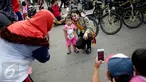 Seorang anak berfoto dengan polisi wanita (Polwan) dari kesatuan Samapta Bhayangkara (Sabhara) Polda Metro Jaya di kawasan Bundaran HI, Jakarta, Minggu (26/3). Polwan bersepeda ini memantau kelancaran car free day. (Liputan6.com/Faizal Fanani)