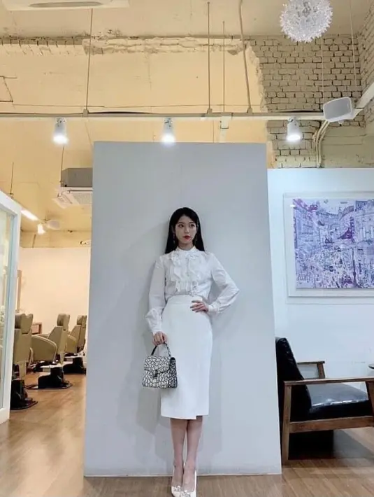 Untuk style feminin dan classy, kamu bisa kenakan blouse dan pencil skirt warna putih ala IU saat memerankan karakter Jang Manwol di drakor Hotel del Luna. (Instagram/jangmanwol_).