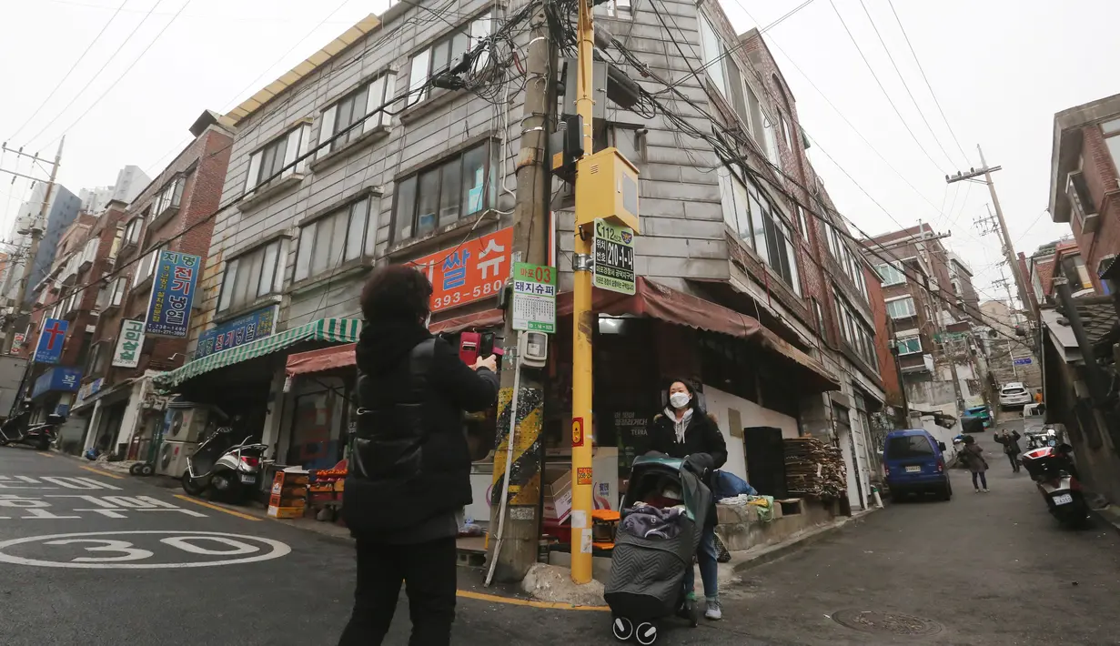 Seorang perempuan mengambil foto di depan sebuah supermarket yang muncul dalam film'Parasite' di Seoul, 15 Februari 2020. Lokasi syuting Parasite di Korea Selatan semakin ramai dikunjungi turis setelah film tersebut berhasil memboyong dan mendominasi di penghargaan Oscar 2020. (AP/Ahn Young-joon)
