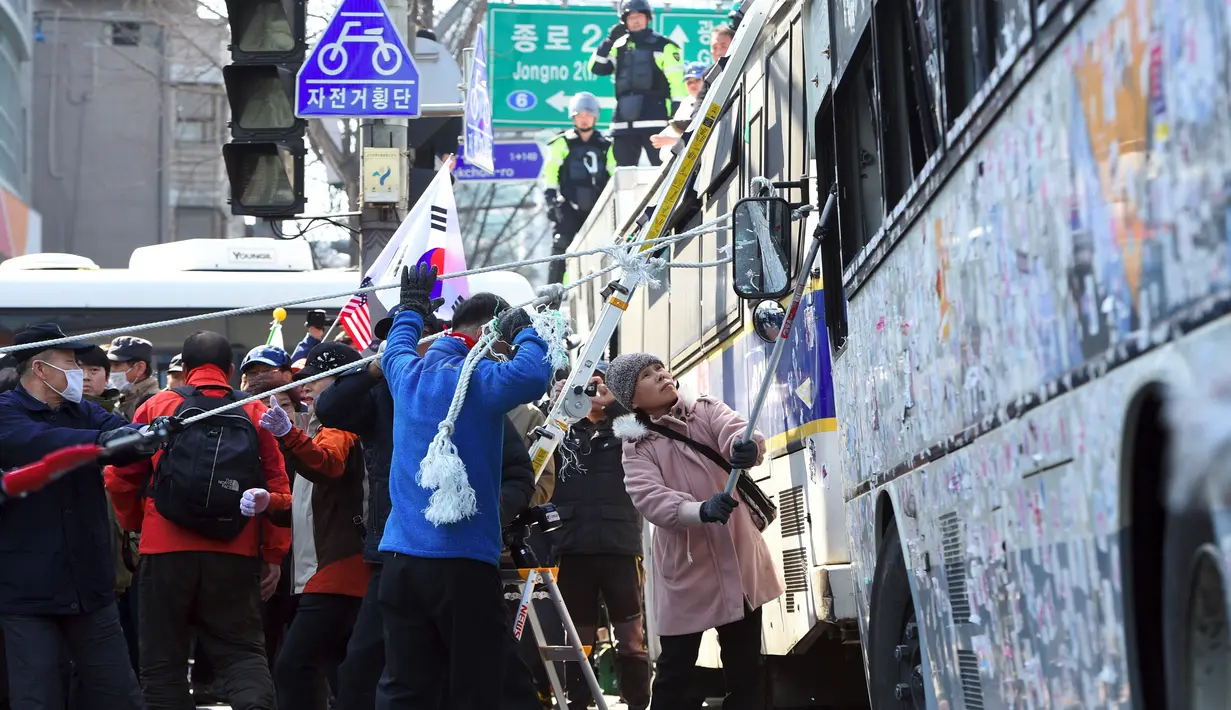Pendukung merusak kendaraan milik polisi saat demo pemakzulan Presiden Korsel, Park Geun-hye di Seoul, Jumat (10/3). Bentrokan terjadi antara demonstran dan polisi usai putusan pemakzulan Geun-hye dibacakan Mahkamah Konstitusi. (JUNG Yeon-Je/AFP)