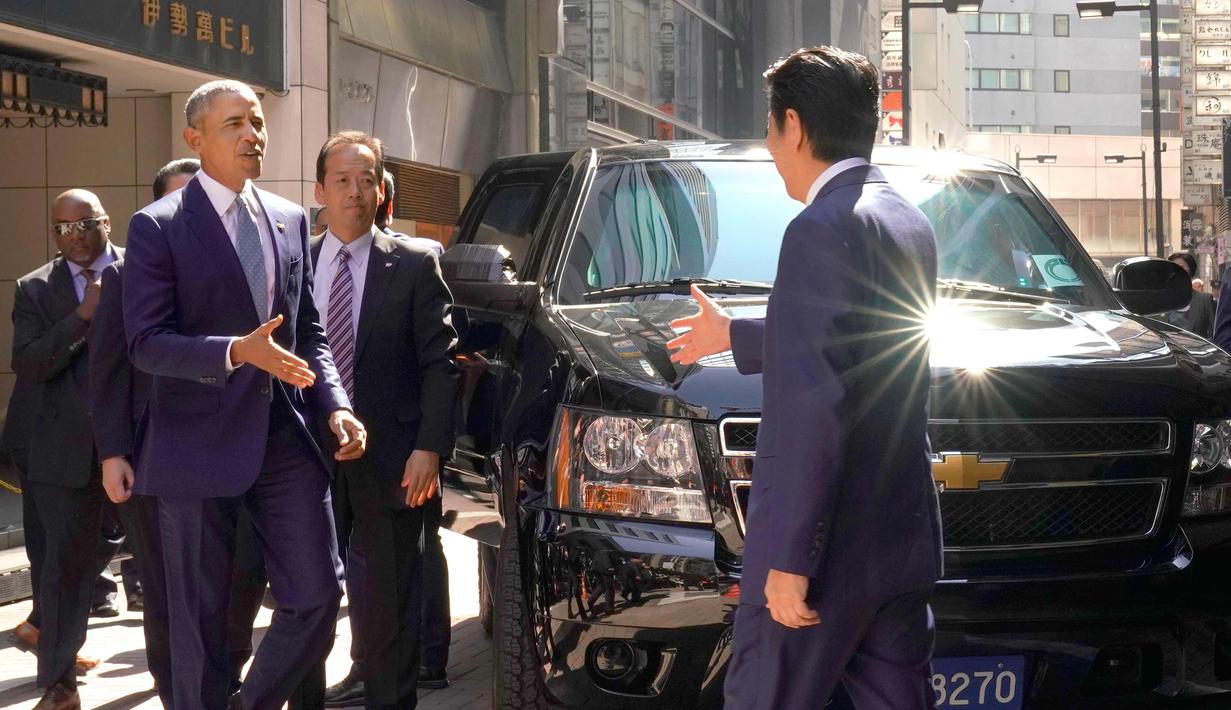 PM Jepang, Shinzo Abe menyambut Presiden AS ke-44 Barack Obama saat tiba di salah satu restoran sushi di kawasan Ginza, Tokyo, Jepang, (25/3). Obama dan Abe makan siang bersama di restoran tersebut. (AP Photo / Shizuo Kambayashi, Pool)