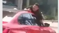 Aksi Nekat Pria 'Nemplok' di Atas Kap Mobil Merah di Jakbar Viral, Polisi Turun Tangan