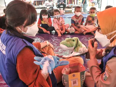 Petugas dari Dinas Sosial DKI Jakarta mengisahkan dongeng dengan boneka saat program trauma healing kepada anak-anak korban kebakaran yang mengungsi di SDN 09 Kebon Kosong, Kemayoran, Jakarta, Selasa (31/8/2021). (merdeka.com/Iqbal S. Nugroho)