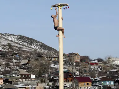 Seorang pria memanjat tiang kayu yang tinggi untuk mendapatkan hadiah selama perayaan Maslenitsa di kota Krasnoyarsk, Rusia, (13/3). perayaan Maslenitsa adalah kegiatan untuk menandai berakhirnya musim dingin di Rusia. (REUTERS / Ilya Naymushin)