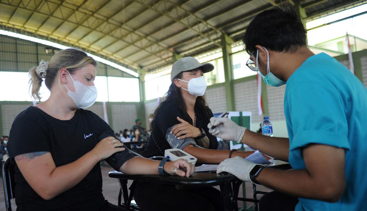 Dua warga negara asing (WNA) menjalani pemeriksaan tekanan darah sebelum menerima vaksin virus corona COVID-19 AstraZeneca di klinik vaksinasi massal darurat di Denpasar, Bali, Selasa (6/7/2021). Indonesia tengah memerangi gelombang infeksi baru yang belum pernah terjadi sebelumnya. (SONNY TUMBELAKA