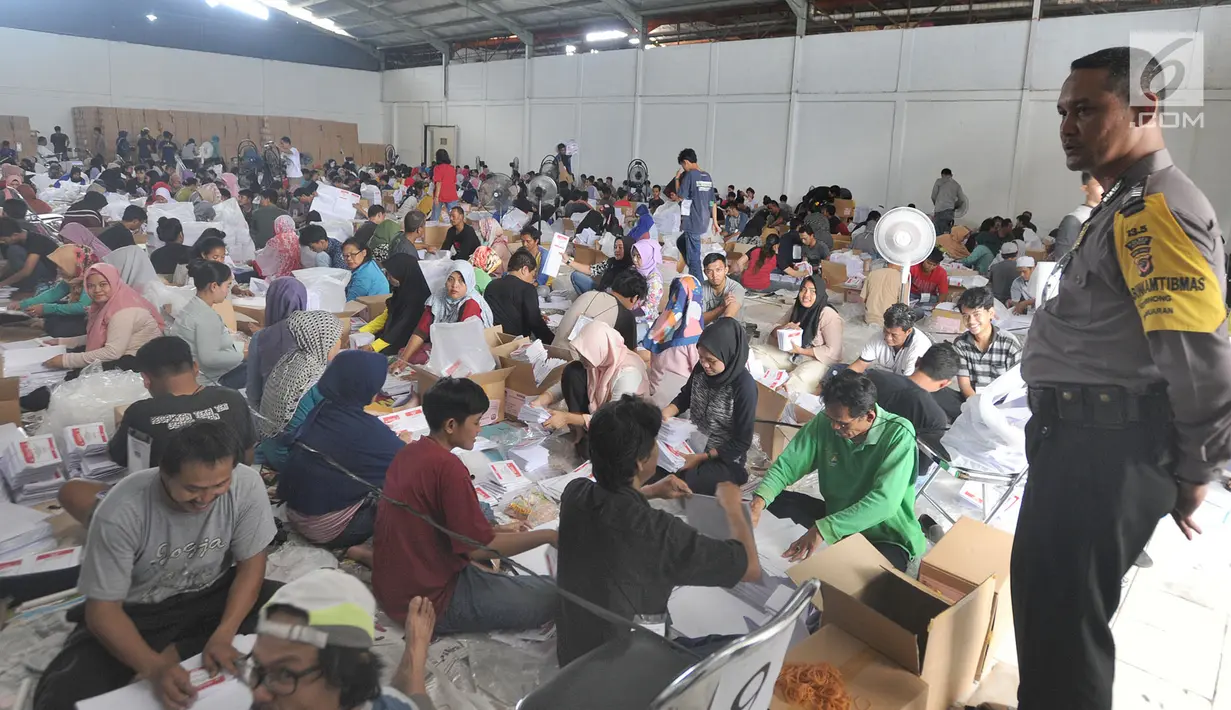 Petugas kepolisian Babinkamtibmas Pabuaran Bogor mengawasi pelipatan kertas suara DPD RI di Gudang KPU, Bogor, Jawa Barat, Kamis (21/2). 650 relawan dilibatkan dalam penyortiran dan pelipatan  kertas suara Pemilu 17 April 2019. (Merdeka.com/Arie Basuki)