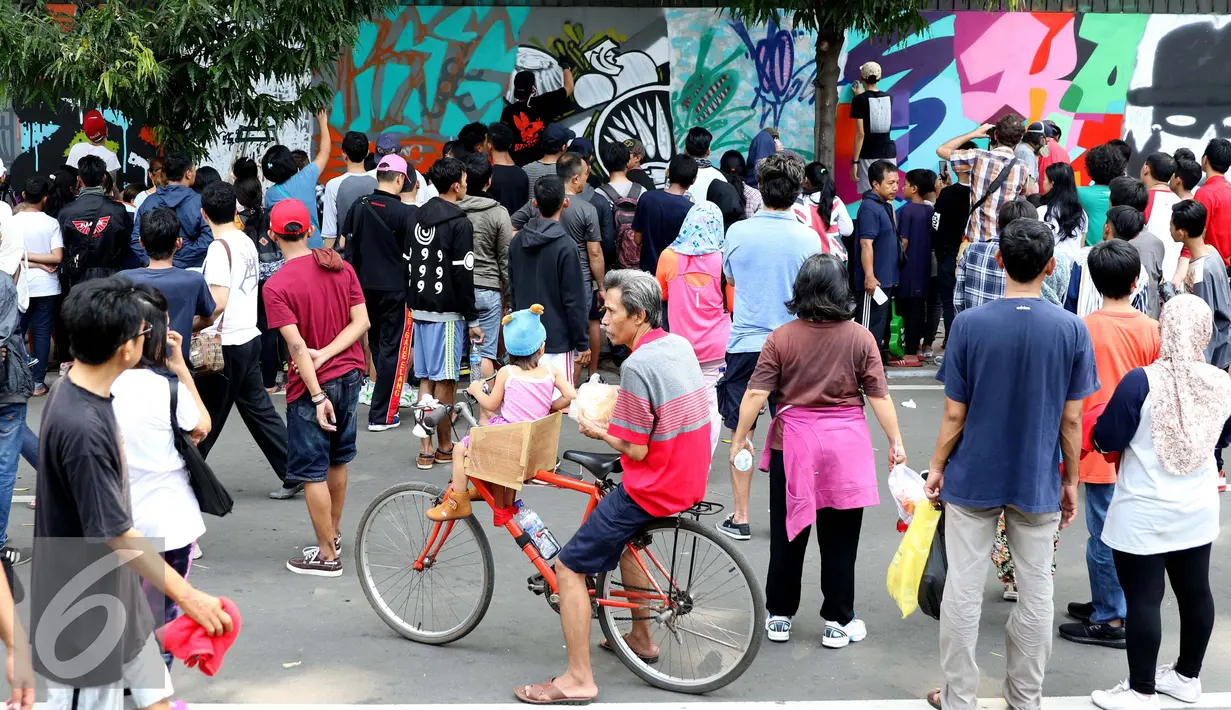 Warga memperhatikan para seniman grafiti saat berkarya di kawasan Thamrin, Jakarta, Minggu (6/11). Gelaran ini memberikan perspektif baru terhadap seni urban sekaligus memperkenalkan para seniman Grafitti di Indonesia. (Liputan6.com/Gempur M. Surya)
