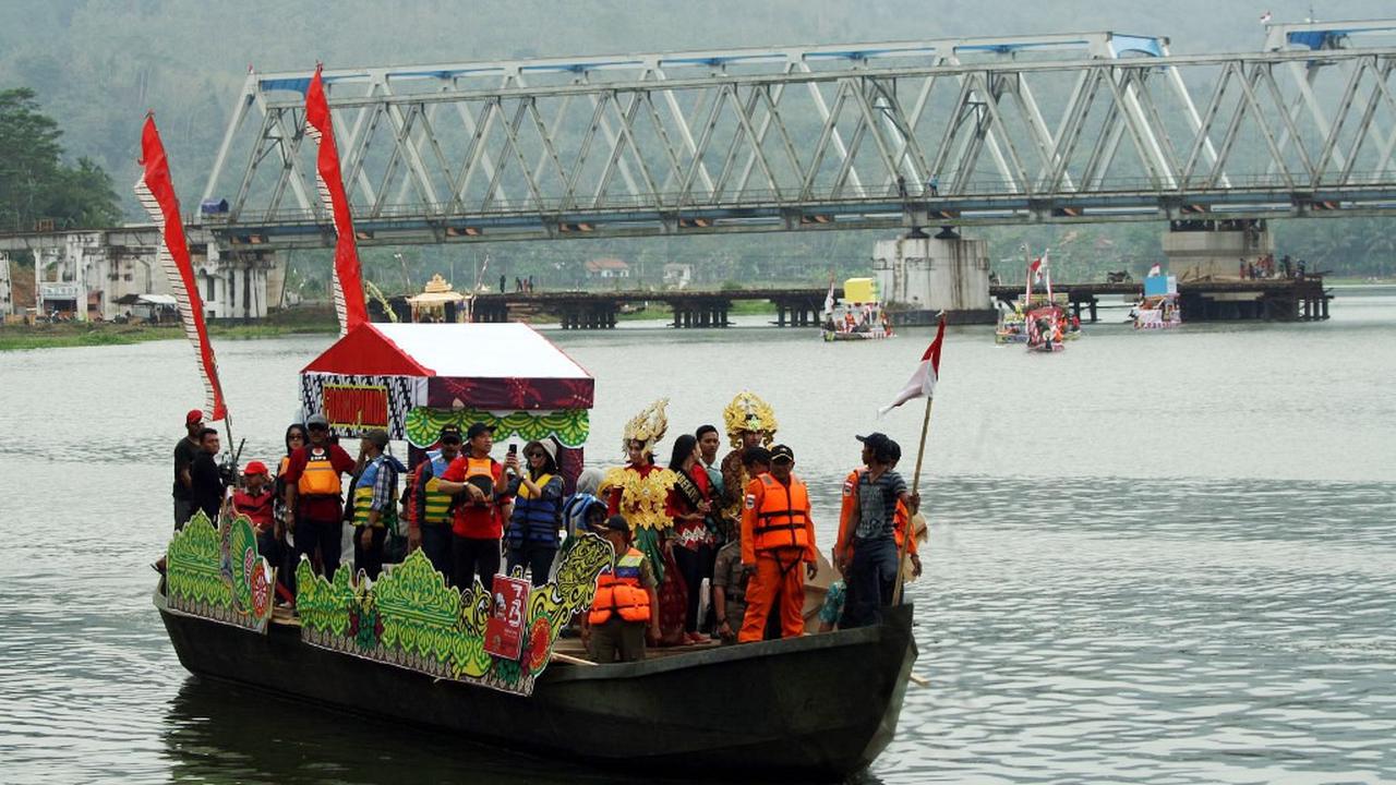 Perahu hias Festival Serayu Banyumas 2018 berlayar dengan latar Jembatan Kereta Api yang melintang di atas Sungai Serayu. (Foto: Liputan6.com/FSB 2018/Muhamad Ridlo)