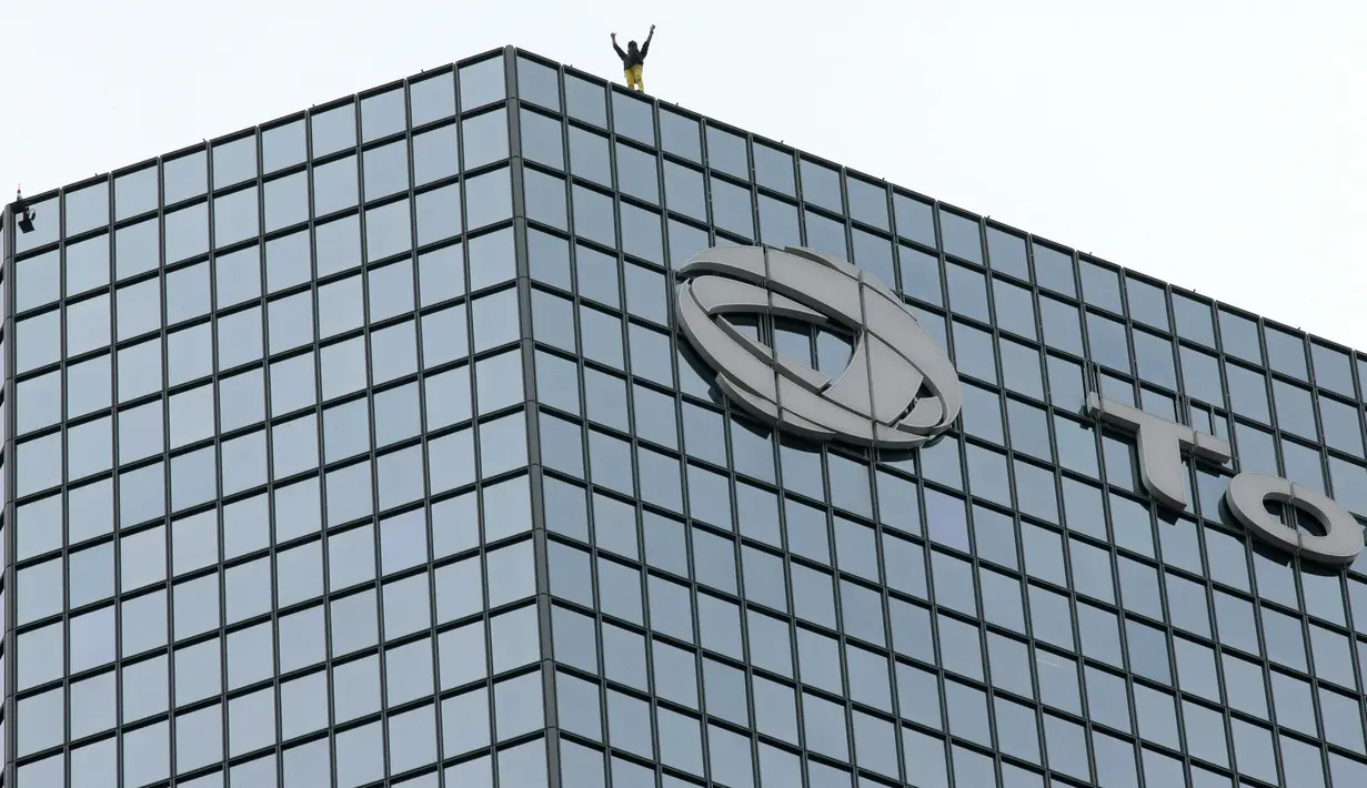 Alain Robert berhasil memanjat gedung di pusat bisnis La Defense, Paris, Prancis, Senin (21/3/2016). Pria yang dijuluki 'Spiderman' ini telah memanjat lebih dari 70 gedung tertinggi di dunia. (Jacques DEMARTHON/AFP)