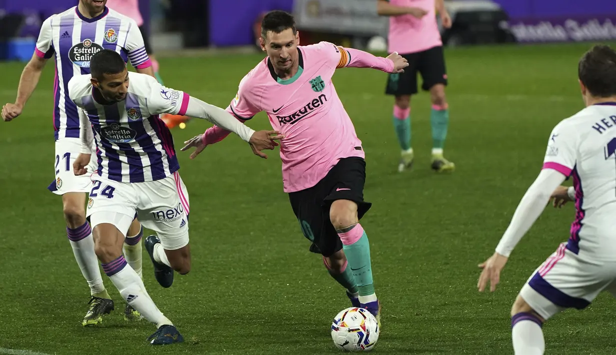 Gelandang Valladolid, Joaquin Fernandez mencoba menahan kapten Barcelona, Lionel Messi pada laga pekan ke-15 Liga Spanyol di Stadion Jose Zorrilla, Selasa (22/12/2020). Messi resmi melewati rekor Pele saat membantu Barcelona menggulung Valladolid 3-0 dalam laga tersebut. (Cesar Manso/Pool via AP)