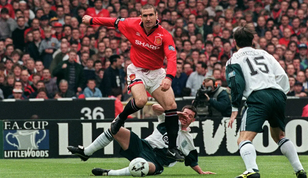 Eric Cantona diangkat sebagai kapten Manchester United pada musim 1996/97 menggantikan Steve Bruce. Pemain yang kerab dijuluki King Eric tersebut merupakan orang asing pertama yang diangkat sebagai kapten. Ia berhasil membawa MU meraih gelar ke-11 Liga Inggris. (AFP/Gerry Penny)