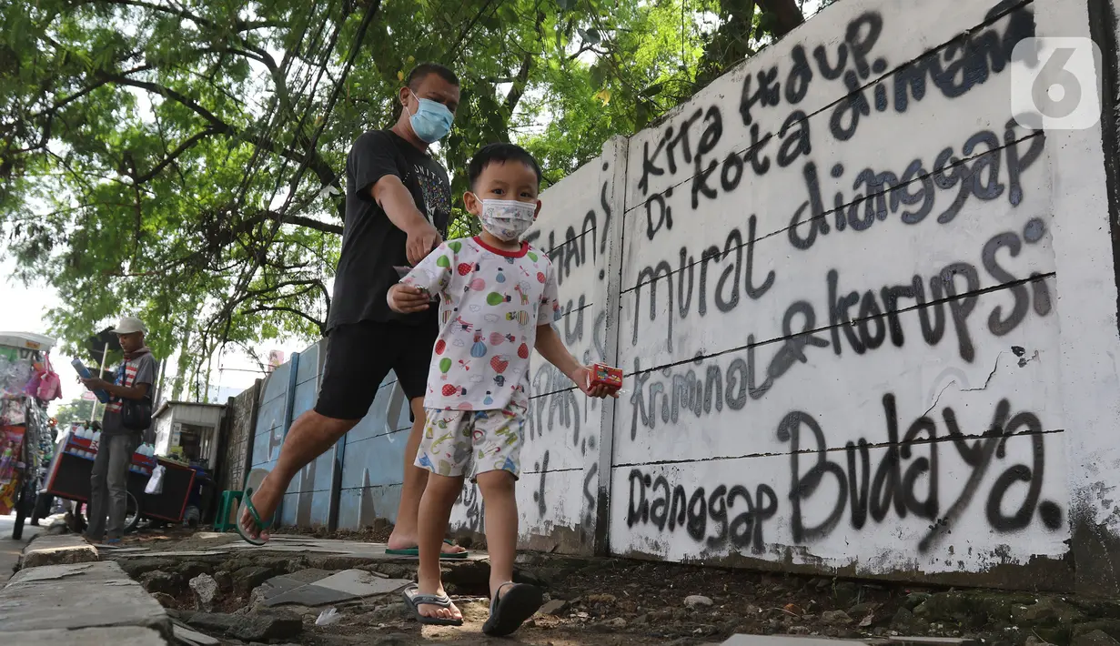 Pejalan kaki melintas di depan mural di Jalan Raya Citayam, Depok, Jawa Barat, Rabu (25/8/2021). Mural tersebut merupakan wujud ekspresi dari sejumlah seniman serta sebagai media penyampaian kritik sosial kepada pemerintah di tengah pandemi COVID-19. (Liputan6.com/Herman Zakharia)