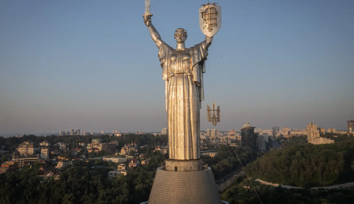 Para pekerja memasang lambang Ukraina pada perisai di tangan monumen tertinggi di negara itu, Monumen Tanah Air, setelah lambang Soviet dihapus, di Kiev, Ukraina, Minggu, 6 Agustus 2023. (AP Photo/Efrem Lukatsky)
