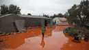 Seorang gadis berjalan melewati genangan air hujan di depan tenda di kamp untuk warga Suriah yang kebanjiran di dekat desa Killi di utara provinsi barat laut Idlib (5/12/2019). (AFP Photo/Aaref Watad)