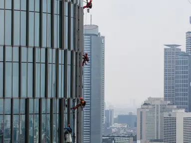 Pekerja membersihkan kaca gedung bertingkat di Jakarta, Jumat (26/02/2021). BP Jamsostek menekankan dua aspek penting terkait pandemi Covid-19, yakni isu kesehatan dan perekonomian dengan jaminan sosial bagi para pekerja dan penerapan K3. (Liputan6.com/Fery Pradolo)