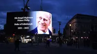 Penghormatan untuk Pangeran Philip, yang meninggal, diproyeksikan ke layar besar di Piccadilly Circus di London, Jumat (9/4/2021). Pangeran Philip menghabiskan sebulan di rumah sakit awal tahun ini sebelum diperbolehkan pulang pada 16 Maret untuk kembali ke Kastil Windsor. (AP/Alberto Pezzali)