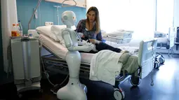 Robot humanoid bernama Pepper berdiri di samping seorang ibu dan bayinya yang baru lahir di rumah sakit AZ Damiaan di Ostend, Belgia (16/6). Rumah sakit ini dibantu dua robot untuk ikut merawat pasien. (REUTERS / Francois Lenoir)