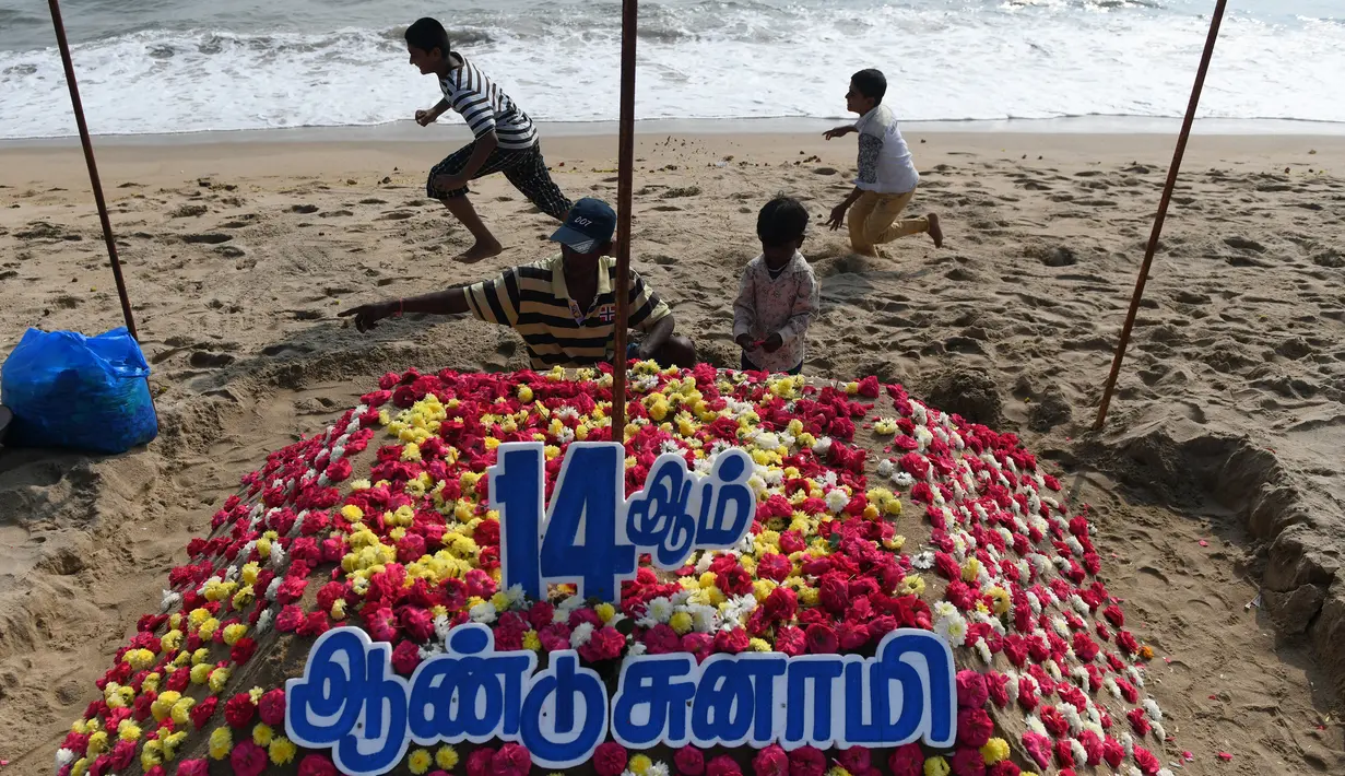 Anggota keluarga menata bunga saat upacara penghormatan untuk korban tsunami tahun 2004 di Pantai Pattinapakkam, Chennai, India, Rabu (26/12). Lebih dari 230 ribu jiwa meninggal dalam tsunami Samudra Hindia pada 2004 lalu. (ARUN SANKAR/AFP)