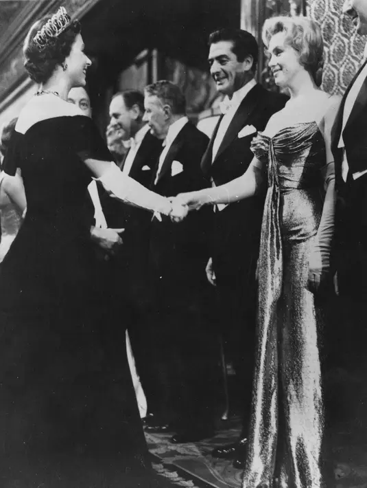 Ini adalah Marilyn Monroe di tahun 1956 saat ia bertemu dengan Ratu Elizabeth. Marilyn Monroe mengenakan strapless dress dengan sarung tangan panjang. Foto: Website.
