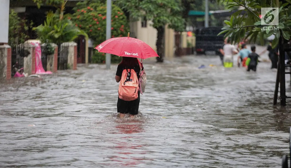 Seorang warga melintasi banjir di jalan Pd. Karya, Jakarta, Kamis (13/12). Hujan yang mengguyur Jakarta Sore tadi menyebabkan banjir setinggi 40cm  menggenangi kawasan Jalan Pd. Karya dan Jalan Bangka. (Liputan6.com/Faizal Fanani)