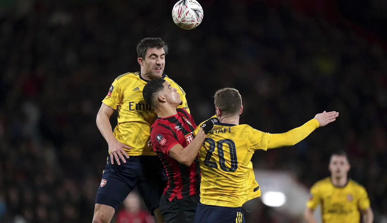 Striker Bournemouth, Dominic Solanke (tengah) berebut bola udara dengan bek Arsenal, Sokratis Papastathopoulos dan Shkodran Mustafi pada pertandingan putaran keempat Piala FA di Stadion Vitalitas, Inggris (27/1/2020).  Arsenal berhasil melaju ke babak kelima Piala FA. (John Walton/PA via AP)