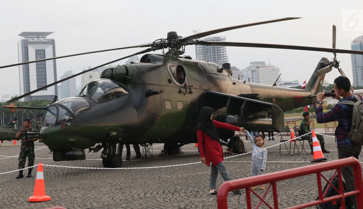 Warga berfoto berlatar helikopter TNI pada pameran Alat Utama Sistem Persenjataan TNI di Kawasan Monas, Jakarta, Kamis (27/9). Pameran ini bagian perayaan HUT TNI ke-73. (Liputan6.com/Helmi Fithriansyah)