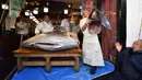 Pekerja jaringan restoran sushi ternama Sushizanmai memegang bagian ikan tuna sirip biru seberat 276 kg yang dibeli perusahaannya di restoran utama mereka di Tokyo, Minggu (5/1/2020). Tuna raksasa itu dibeli dalam lelang perdana 2020 dengan harga sekitar Rp 24 miliar. (Kazuhiro NOGI / AFP)