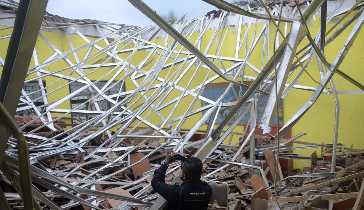 Seorang jurnalis lokal merekam kerusakan ruang kelas di sebuah sekolah setelah gempa bumi di Malang, Jawa Timur, Sabtu (10/4/2021). Gempa bumi yang kuat merusak bangunan di pulau utama Indonesia di Jawa dan mengguncang tempat wisata di Bali, kata pejabat Sabtu. (AP Photo/Hendra Permana)