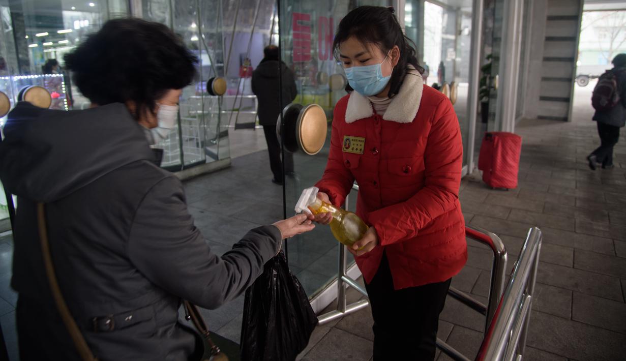 Petugas menyemprotkan sanitizer ke pengunjung di dalam Pyongyang Department Store No. 1, Korea Utara (28/12/2020). Meski Korea Utara melaporkan nol kasus Covid-19, pemerintahan Pyongyang tetap menerapkan standar protokol kesehatan guna mencegah penyebaran Covid-19. (AFP/Kim Won Jin)