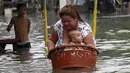 Seorang ibu membawa anaknya menyeberangi banjir di Kota Longos, Malabon City, Manila Utara, Filipina (6/7/2015). Akibat badai aktivitas penerbangan, pelabuhan dan sekolah-sekolah ditutup. (REUTERS/Romeo Ranoco)