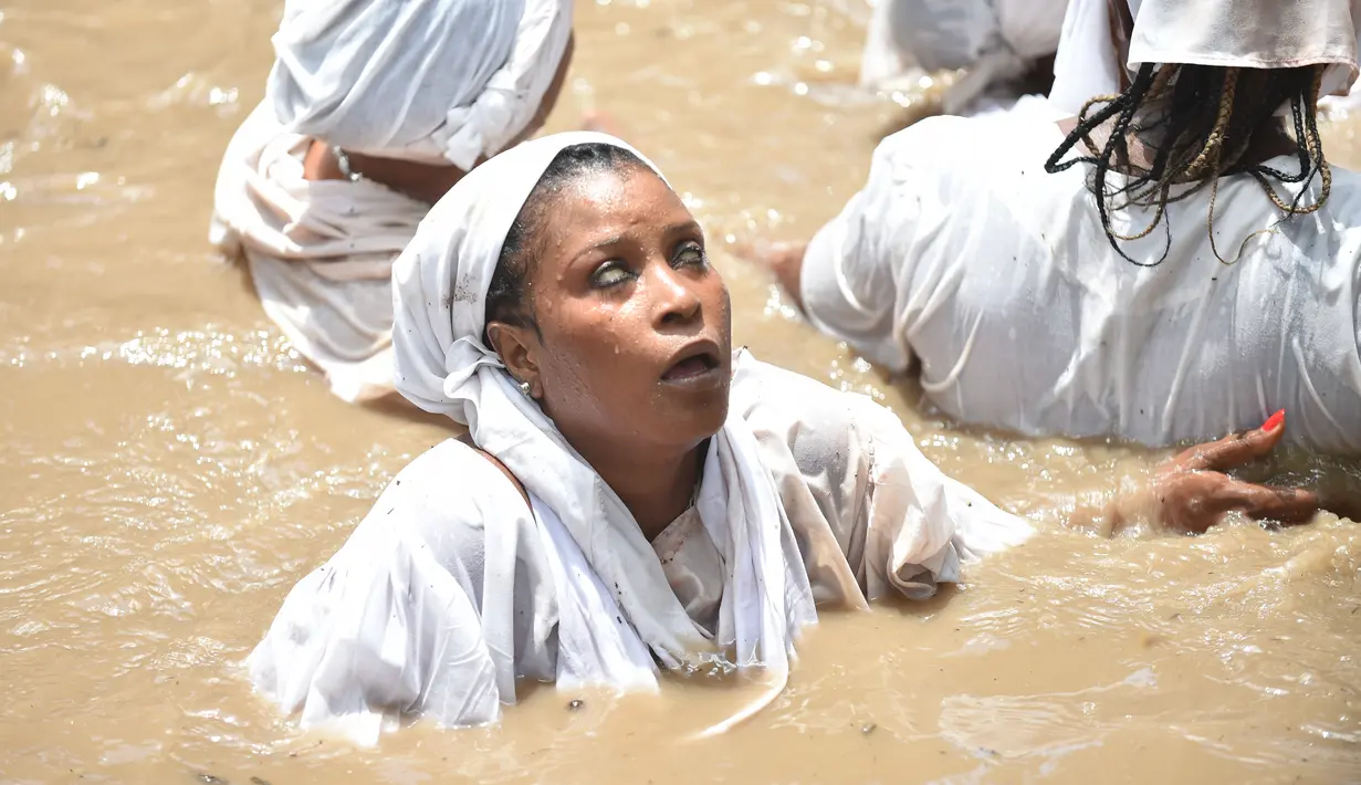Seorang wanita pengikut Voodoo Haiti mandi di kolam suci selama upacara voodoo di Souvenance, Haiti (4/1). Voodoo dibawa ke Haiti oleh para budak dari Afrika Barat. (AFP/Hector Retamal)
