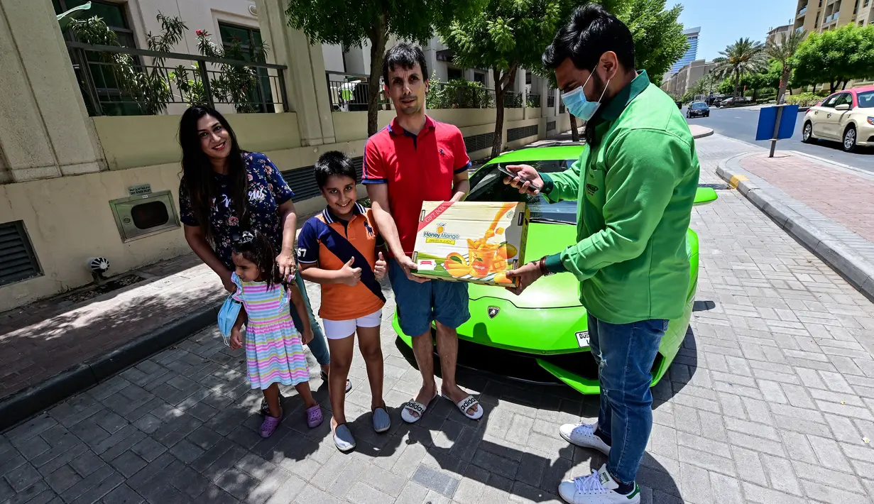 Direktur Pelaksana Pakistan Supermarket Dubai Muhammad Jehanzeb memberikan pesanan mangga kepada sebuah keluarga di Dubai, Uni Emirat Arab, Kamis (2/7/2020). Supermarket tersebut mengantarkan pesanan mangga menggunakan Lamborghini Huracan untuk minimal pesanan sekitar USD 27. (CACACE GIUSEPPE/AFP)
