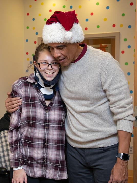 Mantan Presiden AS, Barack Obama memeluk seorang pasien anak di Children's National Medical Center , Washington, Rabu (19/12). Kedatangan Obama yang menyerupai sinterklas itu untuk membagikan hadiah kepada anak-anak di sana. (Chuck Kennedy / AFP)
