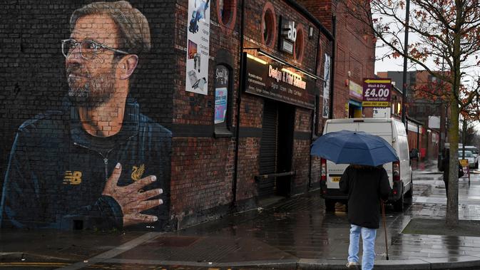 Seorang wanita melintas dekat mural pelatih klub Liverpool, Jurgen Klopp di Jamaica Street, pusat kota Baltic Triangle di Liverpool, Senin (10/12). Pengerjaan mural itu dimulai sejak 8 November 2018 lalu oleh seniman jalanan 
