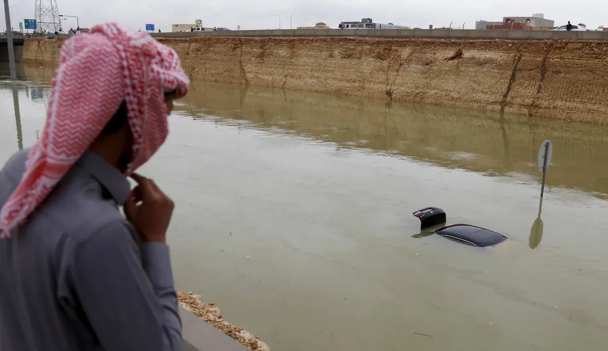 Warga saat melihat lokasi tenggelamnya beberapa kendaraan yang berada dibawah fly over di Riyadh, Arab Saudi, (25/11). Hujan lebat yang mengguyur kota Riyadh menyebabkan banjir di sejumlah titik. (REUTERS/Faisal Al Nasser)