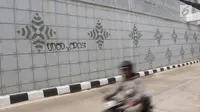 Pengendara motor melintasi coretan di dinding underpass atau lintas bawah Matraman, Jakarta Selatan, Rabu (2/5). Underpass yang belum genap sebulan diresmikan untuk diuji coba tersebut dihiasi coretan tangan jahil. (Liputan6.com/Arya Manggala)