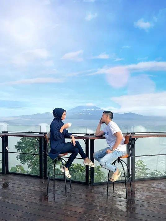 Citra Kirana dan Rezky Aditya tampil mesra menikmati alam. Duduk bersantai dengan latar belakang pemandangan gunung super indah, Citra Kirana tampil dengan outfit biru navy, sedangkan Rezky Aditya memilih kaus putih lengan pendek dan celana jeans. Foto: Instagram.
