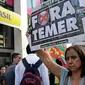 Seorang wanita membawa poster bertuliskan “Keluarkan Temer!” dalam unjuk rasa di Sao Paulo, Brasil, Rabu (2/8). Demonstrasi tersebut bertujuan untuk melengserkan Presiden Brasil Michel Temer yang diduga terkait kasus korupsi. (AP/Andre Penner)