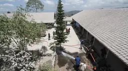 Petugas pemadam kebakaran membersihkan sekolah dari abu setelah Gunung Merapi meletus di Boyolali, Jawa Tengah pada 13 Maret 2023. Pembersihan abu untuk menghindarkan para siswa serta guru dari gangguan abu vulkanik yang ada di kompleks sekolah. (AFP/Dika)