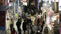 Orang-orang memakai masker untuk mencegah penyebaran virus corona berjalan di pusat perbelanjaan di Tokyo (9/2/2021). Jepang telah memberlakukan UU yang memungkinkan pejabat untuk menegakkan tindakan virus corona dengan menghukum pelanggar perintah wajib dengan denda. (AP Photo/Eugene Hoshiko)