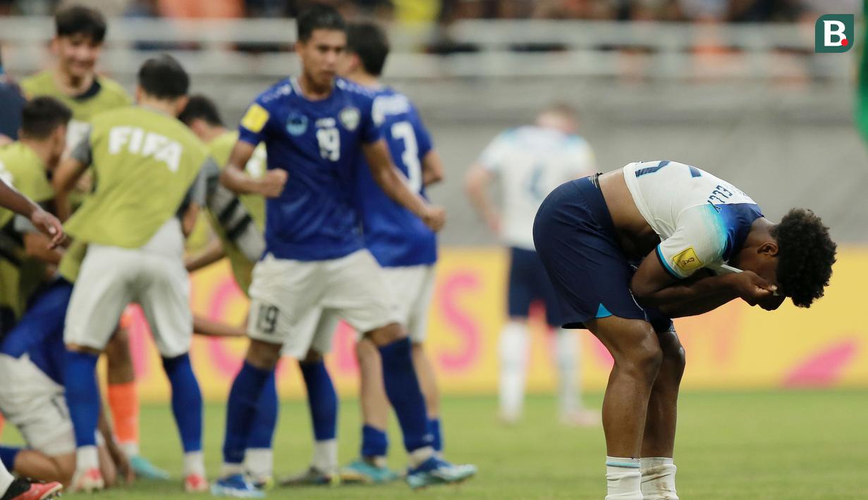 Pemain Timnas Inggris U-17, Myles Lewis-Skelly (kanan), tidak dapat menutupi rasa kesedihannya setelah timnya dikalahkan Timnas Uzbekistan U-17 dalam pertandingan babak 16 besar Piala Dunia U-17 2023 yang berlangsung di Jakarta International Stadium, Rabu (22/11/2023) sore WIB. (Bola.com/M Iqbal Ichsan)