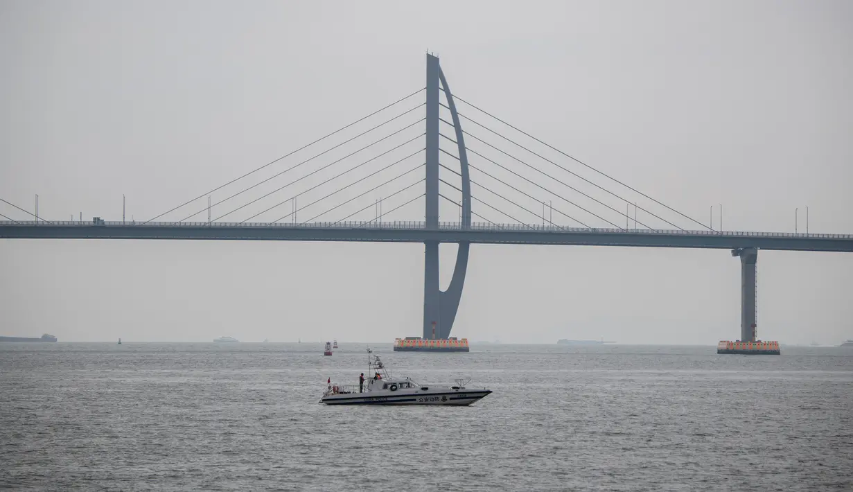 Sebuah kapal melintas di bawah Jembatan Hong Kong-Zhuhai-Makau (HKZM) di Zhuha (22/10). Jembatan laut terpanjang di dunia yang menghubungkan Hong Kong, Makau, dan daratan Cina ini akan dibuka untuk lalu lintas pada 24 Oktober 2018. (AFP Photo/Fred Dufour)