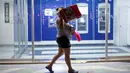 Seorang wanita berjalan usai membawa barang yang ia jarah dari sebuah toko di Veracruz, Meksiko, (4/1). Mereka nekat melakukan aksi vandalisme hingga penjarahan. (AP Photo/Felix Marquez)